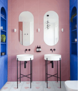 Pair of arched bathroom mirrors mounted above basins in a pink tiled bathroom