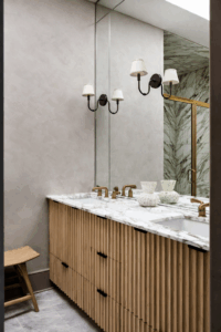 Bathroom mirror above a marble vanity with brass taps and wall lights