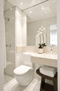 Bathroom wall mirror positioned beside a glass shower enclosure