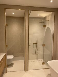 Bespoke glass shower screens with gold fittings in a modern bathroom